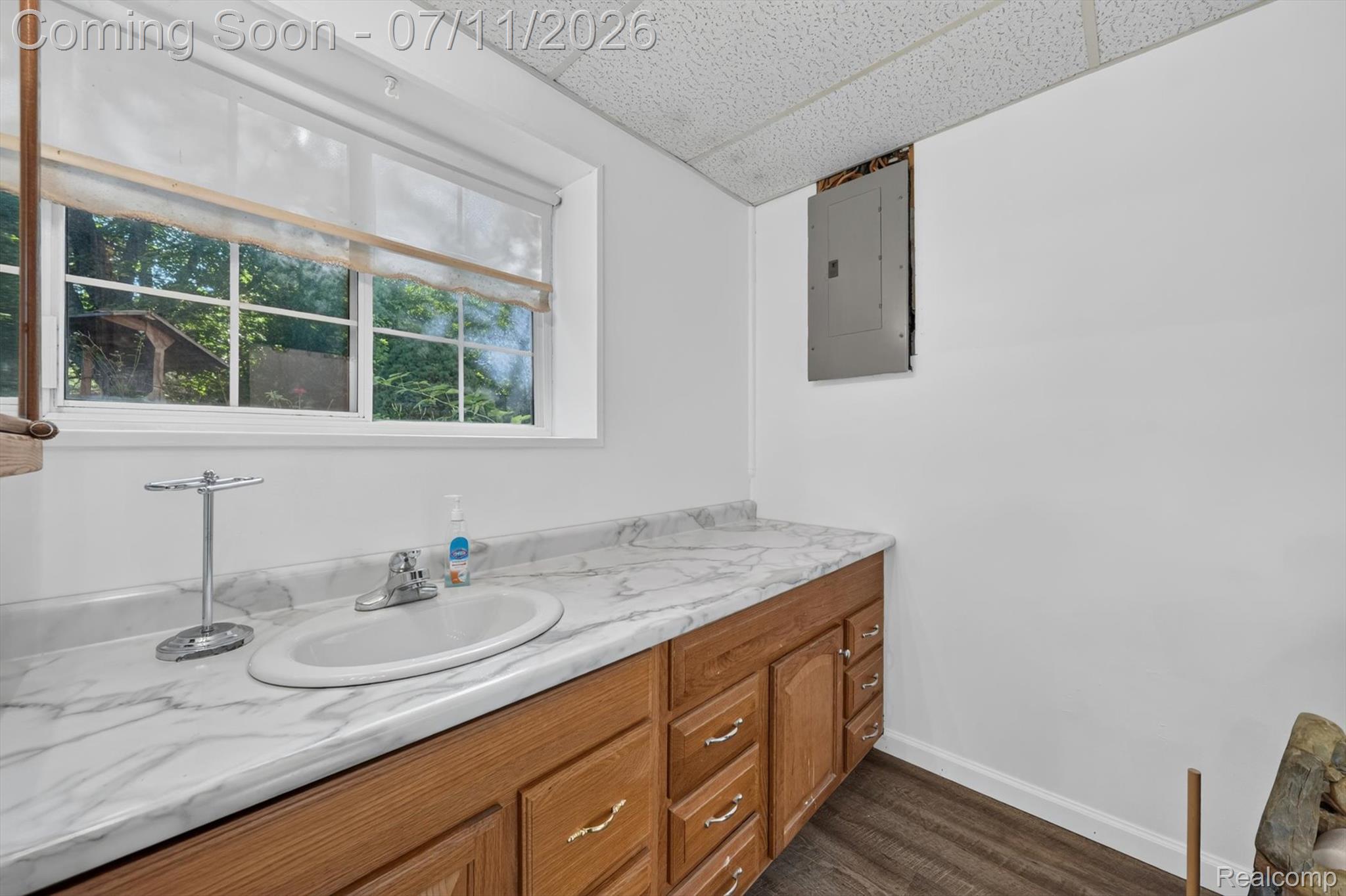 4430 North Center Road Flint, MI 48506 - Photo 29 of 49 Vanity with a built-in oval sink, wood-finish cabinetry, and a marble-patterned countertop
