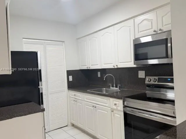 a kitchen with stainless steel appliances granite countertop white cabinets and black stove top oven