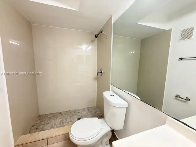 a white toilet sitting next to a bathroom sink and a shower