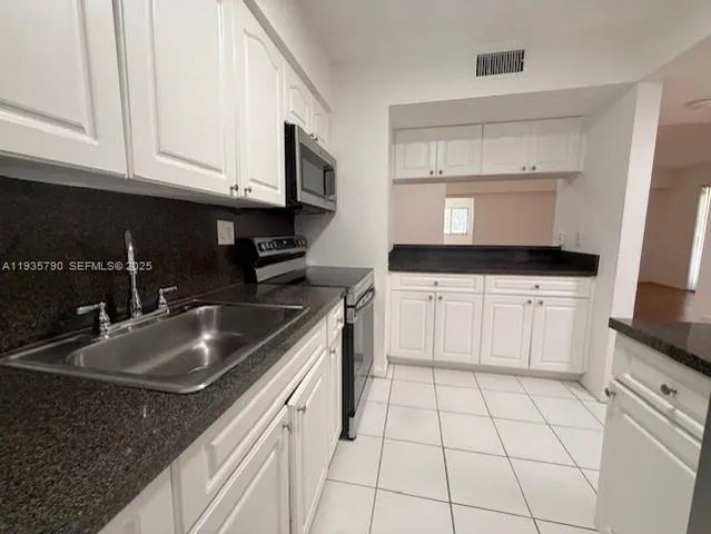 a kitchen with granite countertop a sink a stove and cabinets