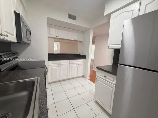 a kitchen with granite countertop a refrigerator a stove a sink and a counter top space