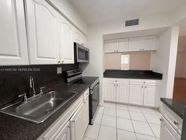 a kitchen with granite countertop a sink a stove and cabinets
