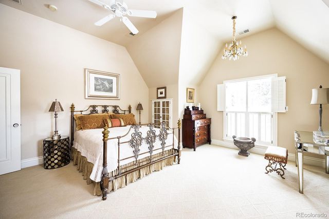 a spacious bedroom with a bed a chandelier and large window
