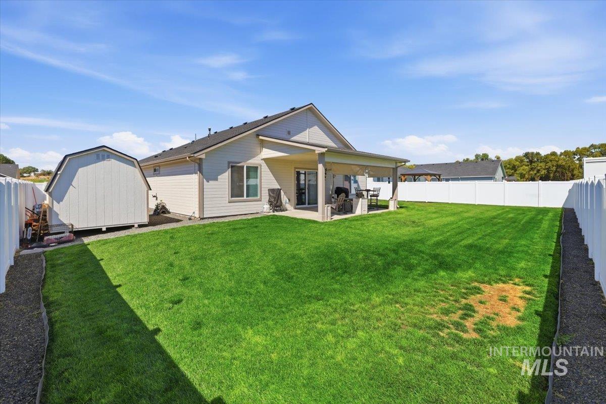 918 Sierra Street Vale, OR 97918 - Photo 32 of 42 Expansive green lawn, white vinyl fencing, covered concrete patio, and a detached storage shed