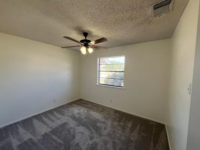 an empty room with a chandelier fan and windows