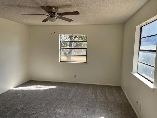 an empty room with windows and fan