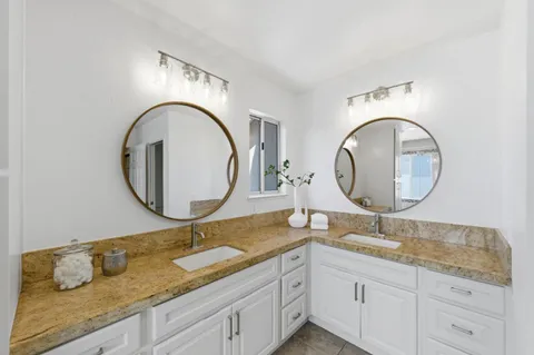 a bathroom with a granite countertop double vanity sink and a mirror