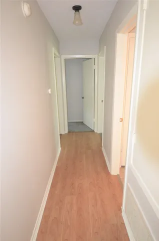 a view of a hallway with wooden floor and a bathroom