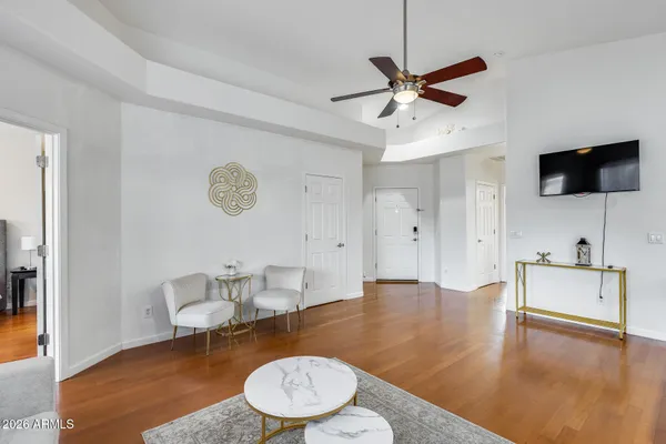 a living room with furniture kitchen view and a wooden floor