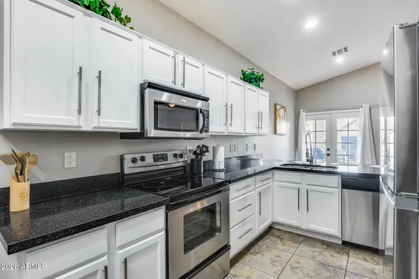 a living room with kitchen island granite countertop wooden floor and a ceiling fan