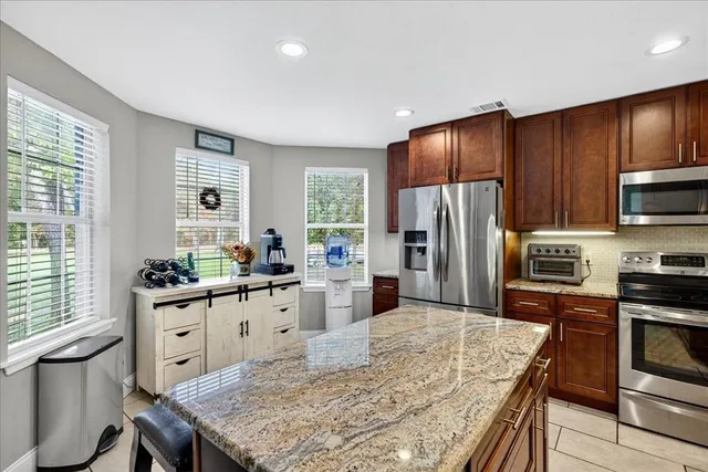 a kitchen with stainless steel appliances granite countertop a refrigerator stove microwave sink and cabinets