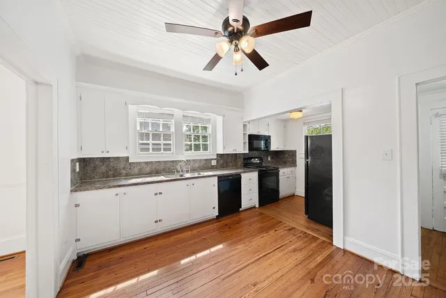a kitchen with granite countertop a sink cabinets stainless steel appliances and a window