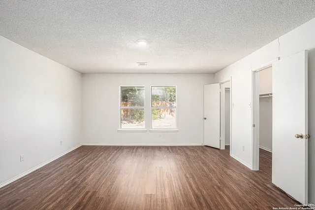 an empty room with wooden floor and window
