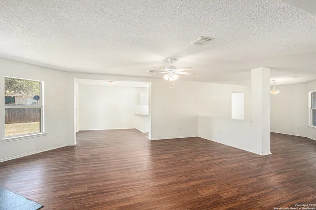 an empty room with wooden floor cabinet and windows