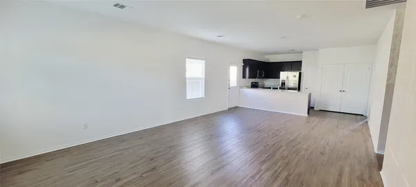 a view of a kitchen and an empty room with wooden floor and a window