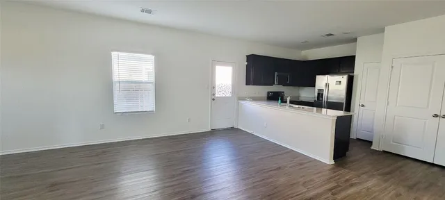 a view of a kitchen with cabinets wooden floor and electronic appliances
