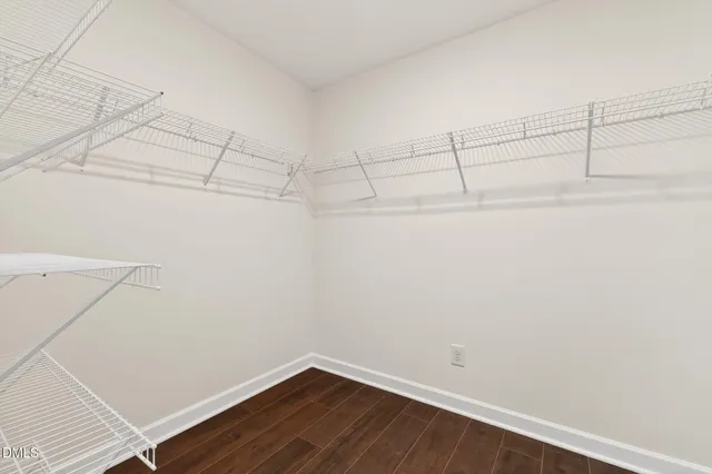 an empty room with wooden floor chandelier fan and windows