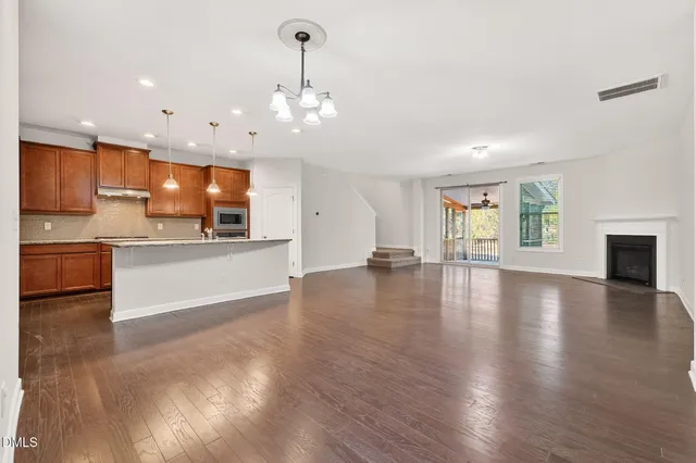 a view of a kitchen with a sink wooden cabinets and a living room