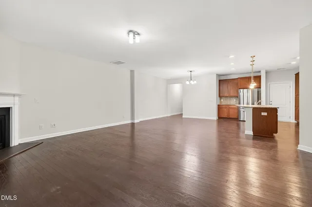 a kitchen with stainless steel appliances kitchen island granite countertop a refrigerator a sink a stove and oven with wooden floor