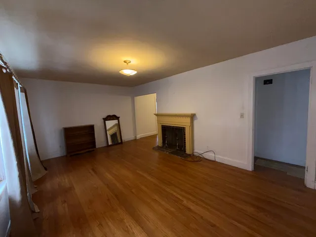 a view of a livingroom with wooden floor and a fireplace
