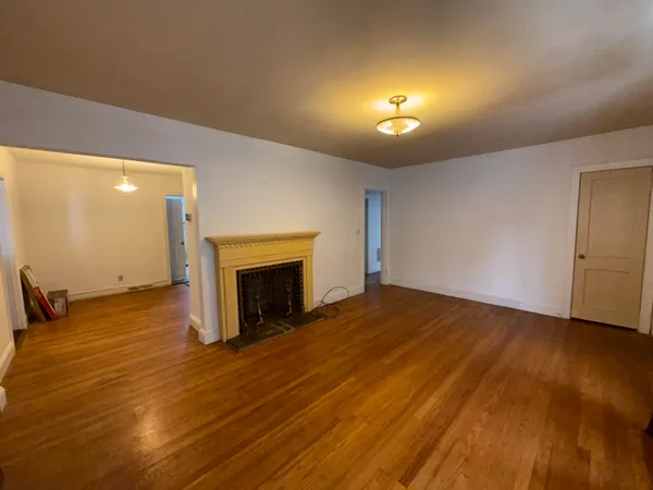 a view of empty room with wooden floor and fireplace