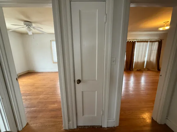 a view of a hallway with wooden floor and a bathroom