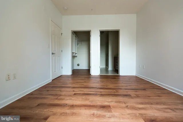 a view of an empty room with wooden floor and closet