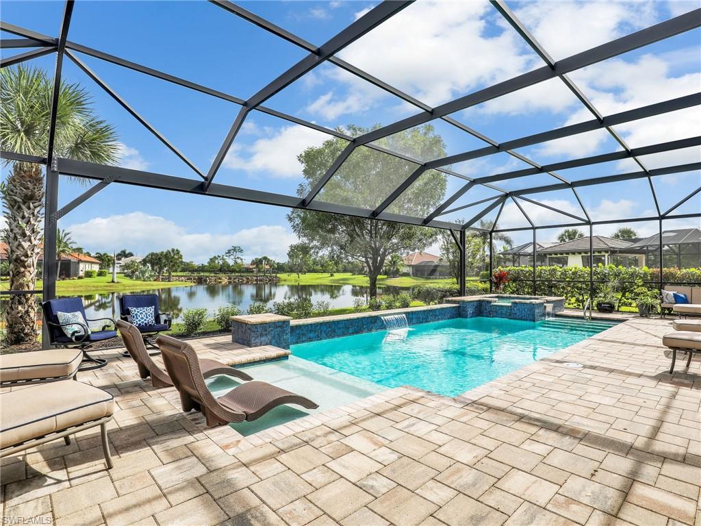 View of pool with a lanai, a sunroom, a pool with connected hot tub, a patio area, and a water view