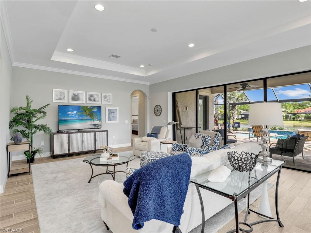 2079 Antigua Lane Naples, FL 34120 - Photo 12 of 44 Living area with wood tiled floors, recessed lighting, a tray ceiling, arched walkways, and a sunroom