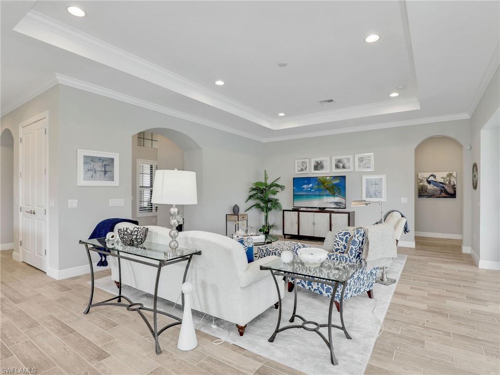 2079 Antigua Lane Naples, FL 34120 - Photo 13 of 44 Living area featuring arched walkways, a tray ceiling, recessed lighting, ornamental molding, and wood tiled floors