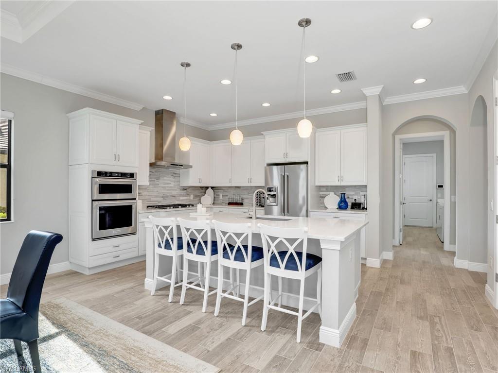 2079 Antigua Lane Naples, FL 34120 - Photo 14 of 44 Kitchen with a kitchen breakfast bar, stainless steel appliances, ornamental molding, arched walkways, and a center island with sink