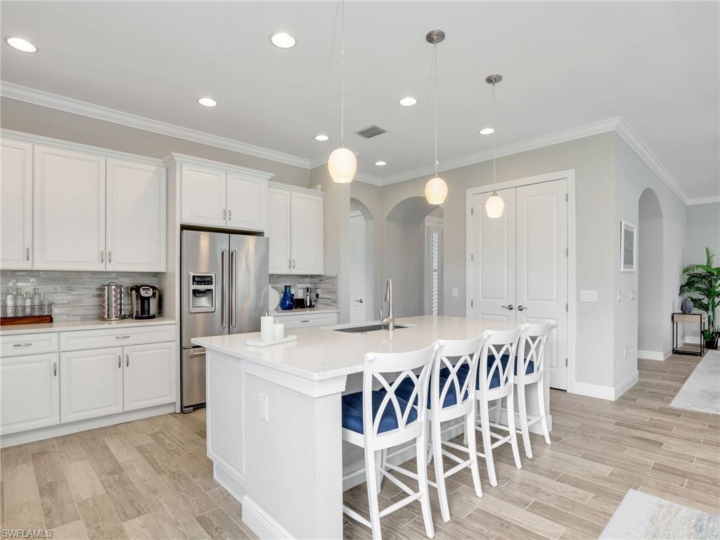 2079 Antigua Lane Naples, FL 34120 - Photo 15 of 44 Kitchen featuring decorative backsplash, arched walkways, high end refrigerator, white cabinets, and ornamental molding