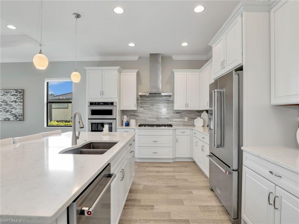 2079 Antigua Lane Naples, FL 34120 - Photo 16 of 44 Kitchen with pendant lighting, light stone countertops, ornamental molding, recessed lighting, and white cabinets