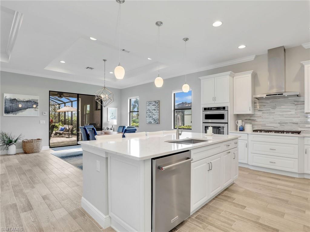 2079 Antigua Lane Naples, FL 34120 - Photo 17 of 44 Kitchen with a tray ceiling, white cabinetry, recessed lighting, decorative backsplash, and appliances with stainless steel finishes