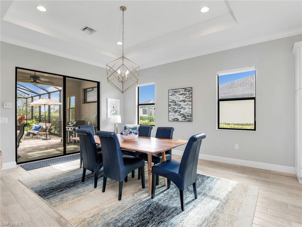 2079 Antigua Lane Naples, FL 34120 - Photo 18 of 44 Dining room featuring a tray ceiling, light wood finished floors, plenty of natural light, recessed lighting, and crown molding