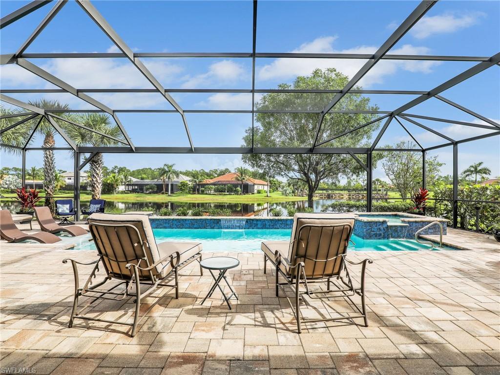 2079 Antigua Lane Naples, FL 34120 - Photo 21 of 44 View of pool featuring a patio, a sunroom, a pool with connected hot tub, a water view, and glass enclosure