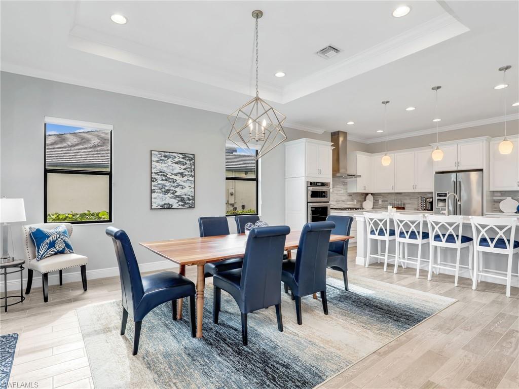 2079 Antigua Lane Naples, FL 34120 - Photo 24 of 44 Dining space featuring a tray ceiling, crown molding, light wood-type flooring, a chandelier, and recessed lighting