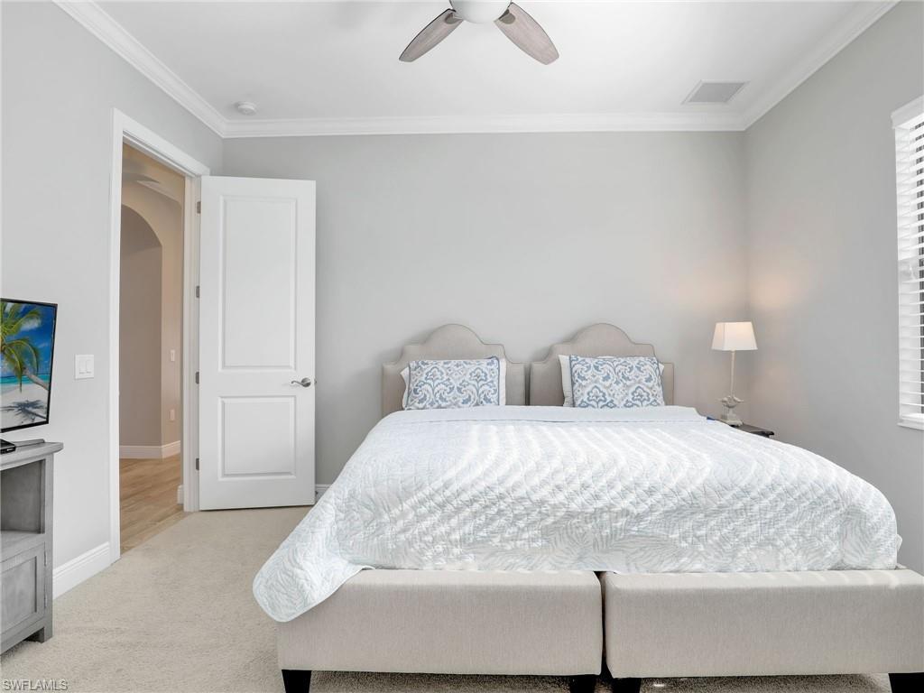 2079 Antigua Lane Naples, FL 34120 - Photo 28 of 44 Bedroom with arched walkways, ornamental molding, a ceiling fan, and carpet floors