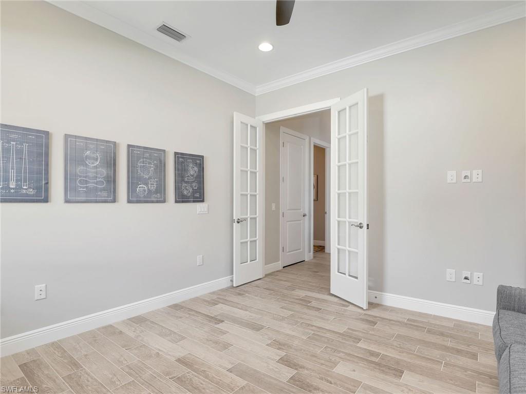 2079 Antigua Lane Naples, FL 34120 - Photo 29 of 44 Empty room with french doors, crown molding, wood tiled floors, and recessed lighting