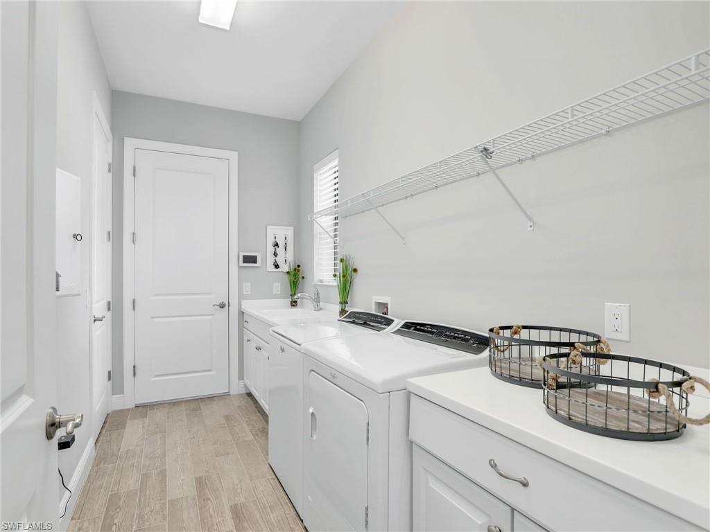 2079 Antigua Lane Naples, FL 34120 - Photo 34 of 44 Laundry area featuring light wood-style floors, cabinet space, and washer and dryer
