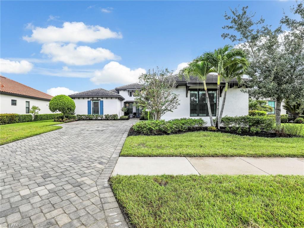 2079 Antigua Lane Naples, FL 34120 - Photo 4 of 44 View of front facade featuring a front lawn, stucco siding, and decorative driveway