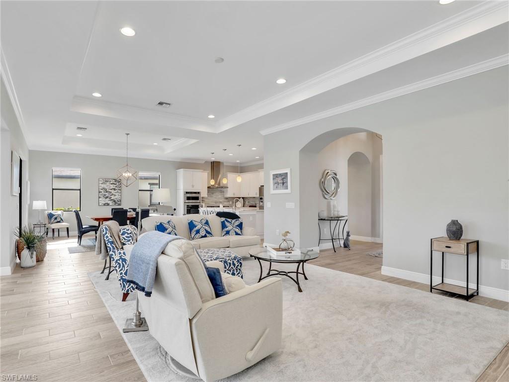 2079 Antigua Lane Naples, FL 34120 - Photo 10 of 44 Living room with a raised ceiling, recessed lighting, light wood-style flooring, arched walkways, and crown molding
