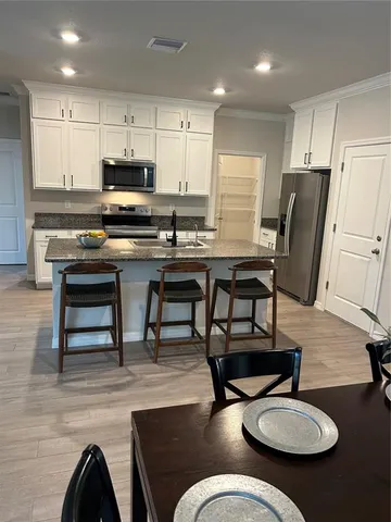a kitchen with stainless steel appliances kitchen island granite countertop a table chairs stove and white cabinets