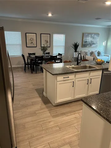 a kitchen with stainless steel appliances granite countertop a table chairs sink and cabinets
