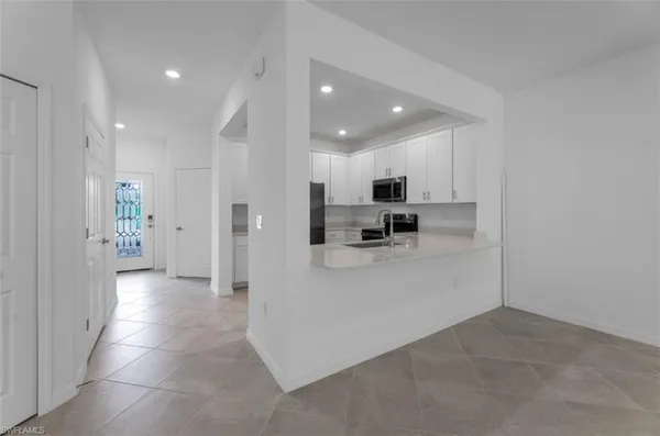 a view of a kitchen with refrigerator and white cabinets