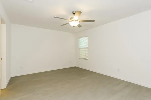 an empty room with chandelier fan and window
