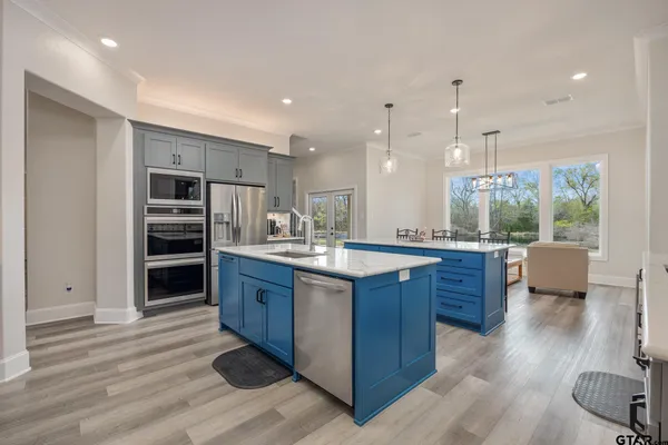 a kitchen with stainless steel appliances granite countertop a stove a sink dishwasher and a refrigerator with wooden floor
