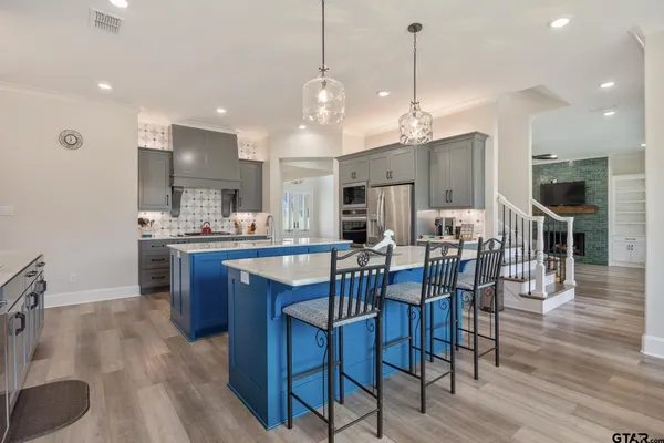 a kitchen with stainless steel appliances kitchen island granite countertop a dining table chairs and sink