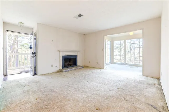 an empty room with windows and fireplace