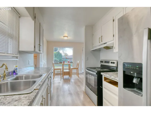 a kitchen with stainless steel appliances granite countertop a sink dishwasher stove and refrigerator